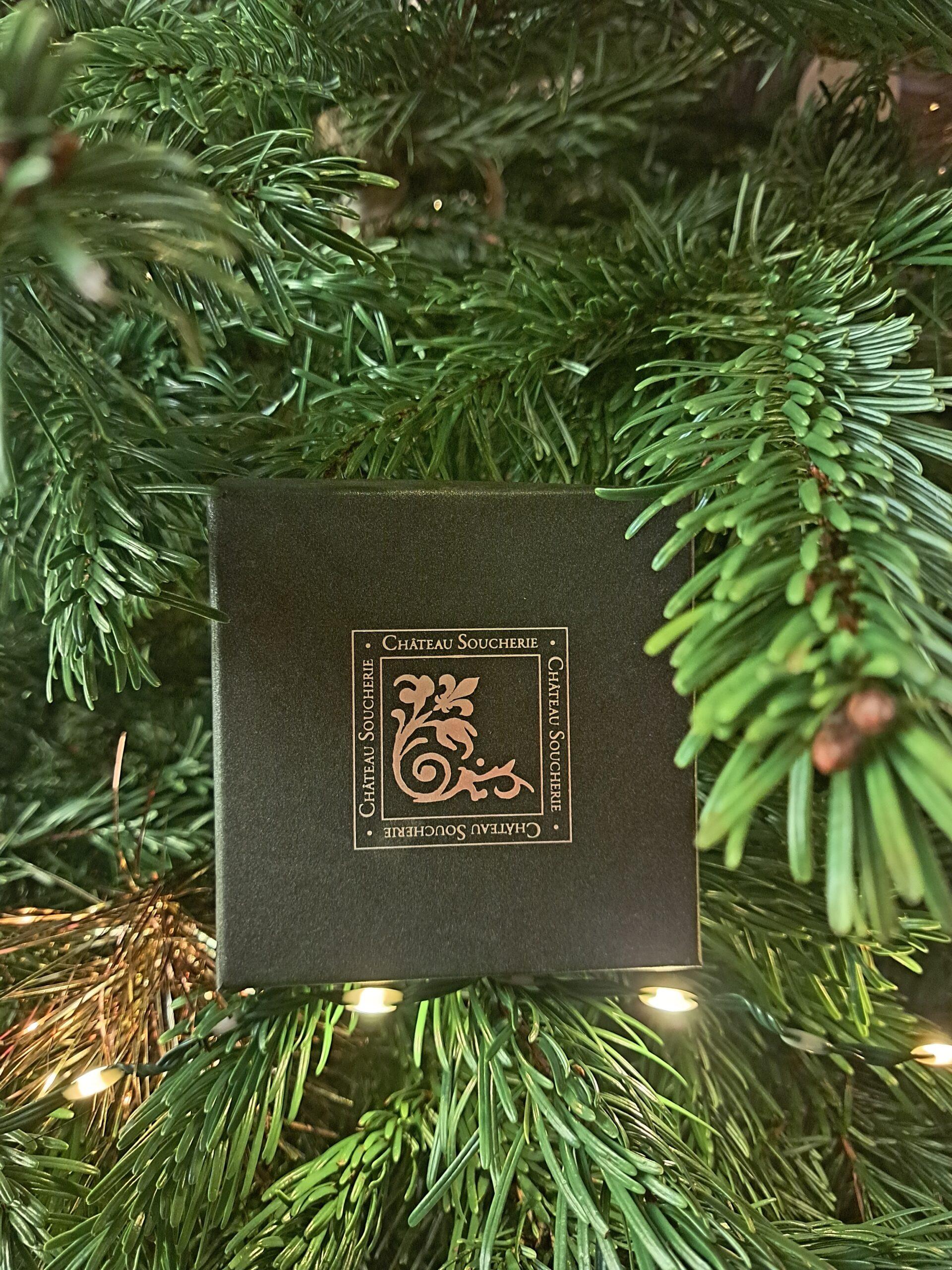 Coffret Soucherie Box du Château Soucherie placé dans un sapin de Noël, idée cadeau élégante pour les fêtes de fin d’année.